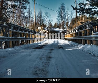 Pont couvert de neige dans un parc sous la lumière du soleil et un ciel bleu Banque D'Images