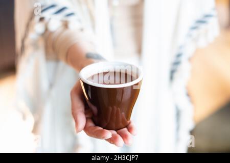 Cérémonie de cacao.Main féminine tenant une tasse de pure boisson chamaniste de cacao cérémonial. Banque D'Images