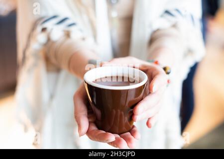 Cérémonie de cacao.Main féminine tenant une tasse de pure boisson chamaniste de cacao cérémonial. Banque D'Images