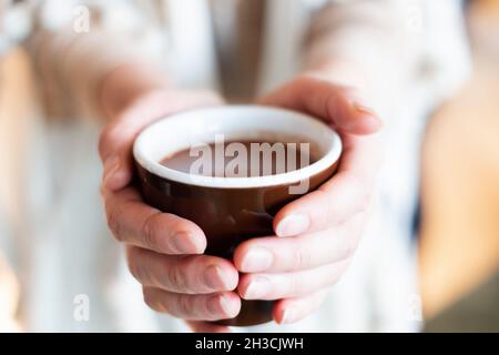 Cérémonie de cacao.Main féminine tenant une tasse de pure boisson chamaniste de cacao cérémonial. Banque D'Images