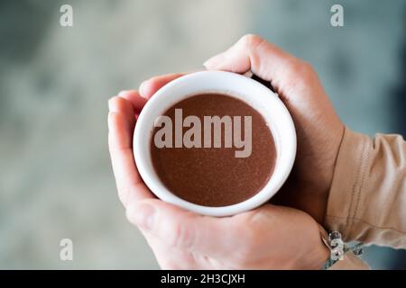 Cérémonie de cacao.Main féminine tenant une tasse de pure boisson chamaniste de cacao cérémonial. Banque D'Images