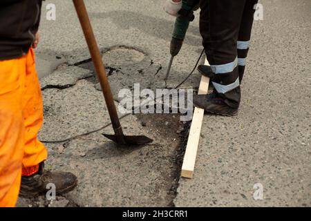 Pelle en main.Le marteau-piqueur est en marche.Les travailleurs réparent l'asphalte.Remplacement de la surface de la route. Banque D'Images