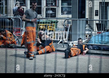 LONDRES, ROYAUME-UNI - 26 mai 2018: Les travailleurs pendant le déjeuner frein reposant sur le sol à Londres Banque D'Images