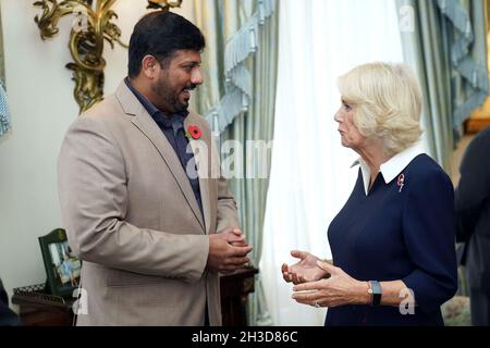 La duchesse de Cornwall s'entretient avec Mirza Shahzad, 36 ans, qui a soutenu l'appel du coquelicot à Bristol, Cardiff, Swansea,Gloucester et Gloucester depuis qu'il a déménagé au Royaume-Uni du Pakistan en 2012, alors que le prince de Galles et la duchesse de Cornwall rencontrent dix collectionneurs de la Royal British Legion (RBL) à Clarence House, Londres, lors du lancement officiel de l'appel de pavot centenaire.Date de la photo: Mardi 26 octobre 2021. Banque D'Images