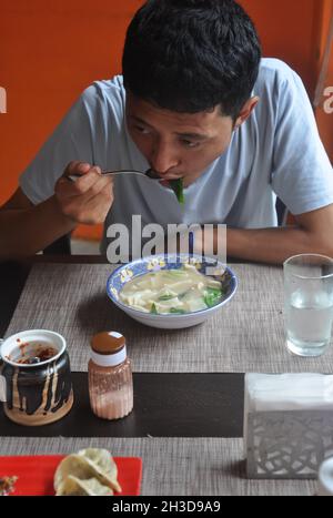 Un homme asiatique mangeant thenthuk (cousin tibétain) dans un café de restauration rapide Banque D'Images