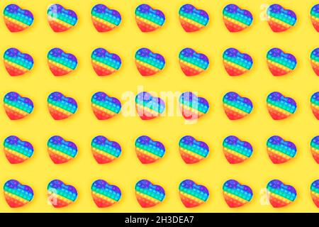 Motif fait de pop IT anti-stress jouet en forme de coeur isolé sur fond jaune. Gros plan. Banque D'Images