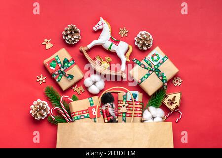 Boîtes cadeau rouges et vertes enveloppées à la main, ornées de rubans, flocons de neige et chiffres, décorations de Noël et décoration en sac sur table rouge Noël Avent Banque D'Images