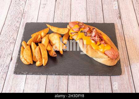 Hot dog avec beaucoup de fromage cheddar fondu, du bacon et des frites Banque D'Images