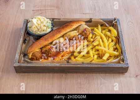 Hot-dog de pain de viande avec tomate et fromage fondu, morceaux d'oignon rouge cru et côté de frites avec coleslaw Banque D'Images