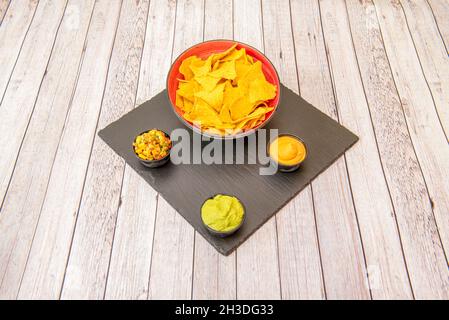 guacamole au pico de gallo avec du maïs doux, de la crème au fromage cheddar et des chips de maïs sur une table en bois Banque D'Images