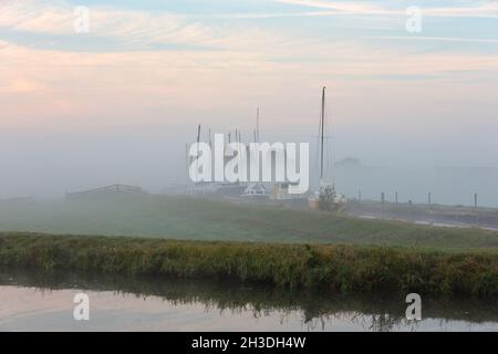 Voiliers et yachts à moteur amarrés dans un port (Botersloot) au milieu des prés, un matin brumeux dans la ville de Warmond, dans le sud de la Hollande Banque D'Images