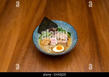 Délicieux miso ramen japonais avec œufs durs, filets de porc, champignons shiitake, algues nori, nouilles,bambou et légumes sur table en bois Banque D'Images