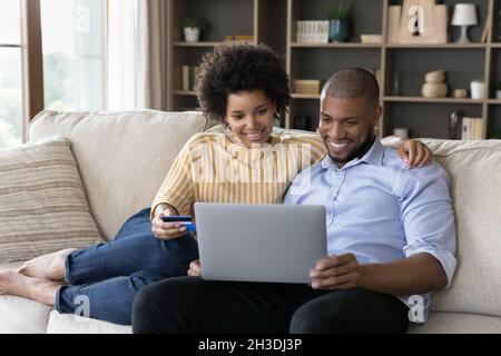 Un jeune couple de familles afro-américaines heureux qui paie des marchandises en ligne. Banque D'Images