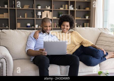Un jeune couple de familles de race mixte souriant utilisant un ordinateur. Banque D'Images