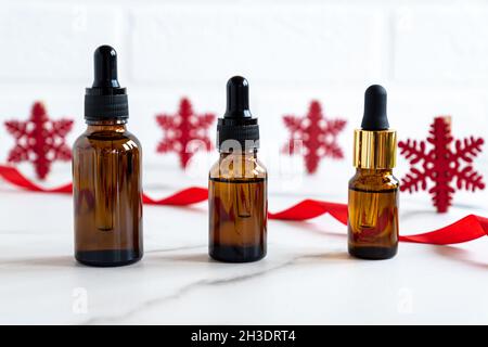 Huile essentielle ou sérum dans une bouteille cosmétique sur une table en marbre avec décoration de Noël.Cosmétiques, soins de la peau en hiver.Bouteille d'huile aromatisée. Banque D'Images