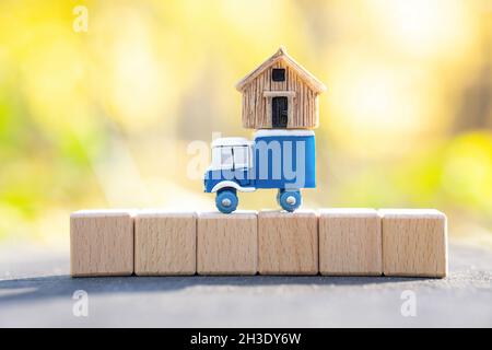 Petit camion de jouets avec une petite maison sur le dessus debout sur une rangée de blocs de bois.Mise au point sur le premier plan, l'espace de copie.Transfert résidentiel et transport de fret Banque D'Images