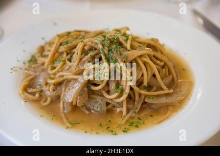 Spaghetti italiens aux oignons, servis dans une assiette blanche Banque D'Images