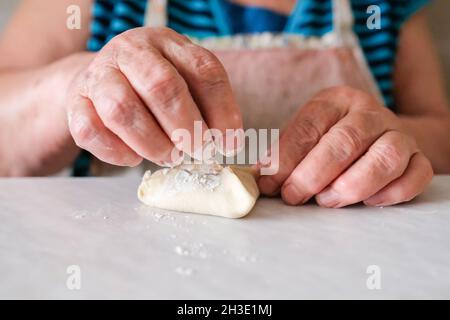 Les mains de grand-mère froissées préparent un plat de pâte Banque D'Images
