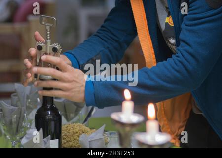 Man ouvre une bouteille de vin rouge, à l'aide d'un tire-bouchon, pendant un dîner Banque D'Images