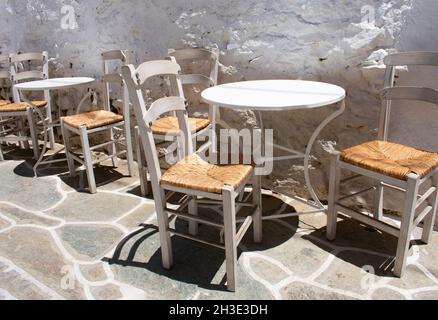 Des tables et des chaises de taverne traditionnelles dans une ruelle étroite, sur la magnifique île grecque isolée de Sikinos vue sur le paysage Banque D'Images