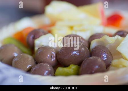 Gros plan d'olives sombres et de cornichons servis dans un bol en plastique Banque D'Images