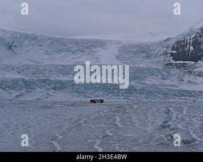 Vue sur un autobus rouge en terre cuite situé sur le glacier Athabasca, une partie du champ de glace Columbia dans les montagnes Rocheuses, exploité par Ice Explorer. Banque D'Images