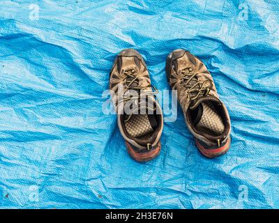 Depuis le dessus des vieilles chaussures de trekking de merde placées sur une tente bleue de camping le jour ensoleillé Banque D'Images