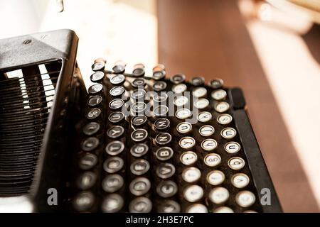 De dessus de l'ancienne machine à écrire noir vintage avec des boutons colorés placés sur la table en plein soleil Banque D'Images