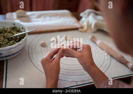 De dessus de la récolte anonyme femelle cuire farce la pâte avec la viande tout en préparant des boulettes chinoises traditionnelles dans la cuisine Banque D'Images