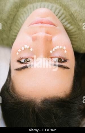 De dessus de la femme calme avec de petites fleurs sous les yeux représentant le concept de soins de la peau et de cosmétiques naturels Banque D'Images
