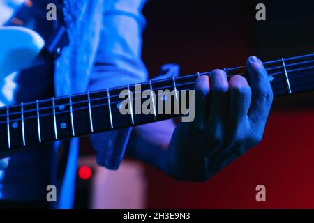 Court guitariste femelle non reconnaissable jouant de la guitare acoustique en club de lumière Banque D'Images