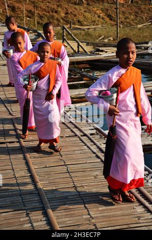 Tradition de l'almsdonnant birman nonnes groupe de procession marche sur le pont pour les gens thaïlandais respect de la prière mettre des offrandes de nourriture le matin à Sangkhla B Banque D'Images