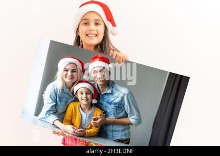 Photo imprimée sur toile, fond blanc.Bonne famille en chapeaux de père Noël célébrant Noël à la maison Banque D'Images