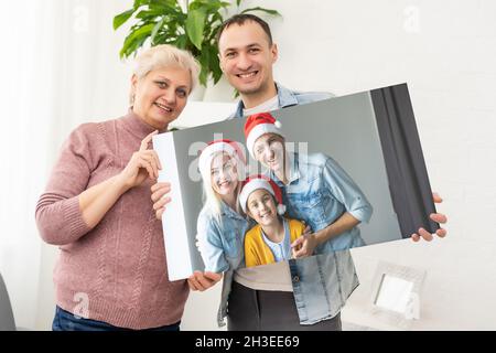 Photo imprimée sur toile, fond blanc.Bonne famille en chapeaux de père Noël célébrant Noël à la maison Banque D'Images