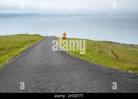 Une route côtière escarpée déserte en Islande par une journée brumeuse Banque D'Images