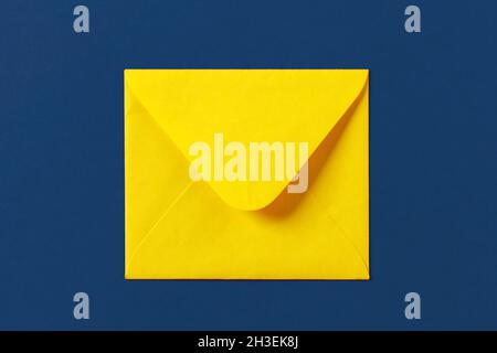 Enveloppe jaune papier sur fond bleu Banque D'Images