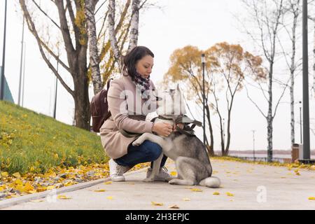 une jeune femme communique avec son chien husky dans le parc côtier d'automne Banque D'Images