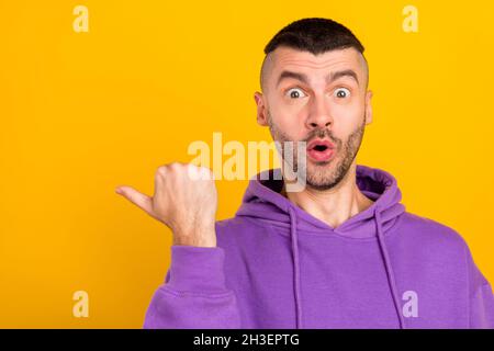 Photo du brunet millénaire impressionné Guy point vide espace porter un pull à capuche violet isolé sur fond jaune Banque D'Images