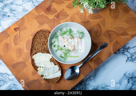 Helsinki / Finlande - 28 OCTOBRE 2021 : cuisine finlandaise traditionnelle : bol de soupe crémeuse au saumon avec garniture à l'aneth.Deux morceaux de pain de seigle sur le côté. Banque D'Images