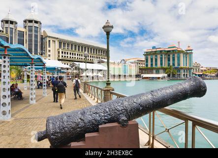 Piétons et vieux canon sur la promenade du front de mer.Port Louis, Maurice, Îles Mascarene. Banque D'Images