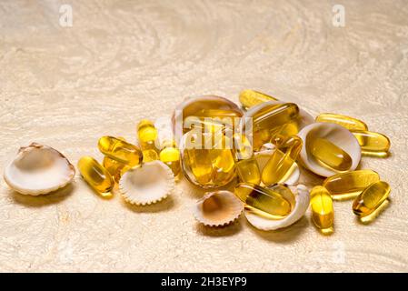 Omega-3 les capsules d'huile de poisson gras tas reposent sur les petites coquilles comme un Trésor.Copiez l'espace pour votre texte.EPA et DHA sont des substances grasses essentielles que ou Banque D'Images