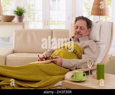 Homme senior qui se nappent dans un fauteuil Banque D'Images