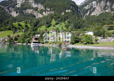 Entre la grande montagne et le lac il y a plusieurs bâtiments dans un petit village. Banque D'Images