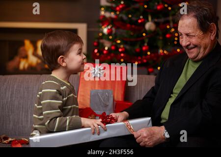 Petit garçon aidant grand-père emballage cadeaux de noël Banque D'Images