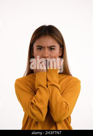 Jeune fille asiatique, nerveuse et attirante, craquant ses ongles en studio Banque D'Images