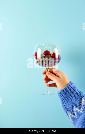 Image créative de Noël avec boules de Noël rouges et dorées en verre.En main sur fond bleu. Banque D'Images