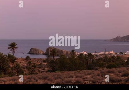 Paysage de palmiers et de rochers près de la petite ville de pêche, Isleta del Moro, au coucher du soleil, dans le parc naturel de Cabo de Gata, Almeria, Espagne Banque D'Images