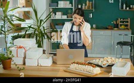 Une femme d'affaires prospère gérant ses travaux d'affaires dans une cuisine confortable Banque D'Images