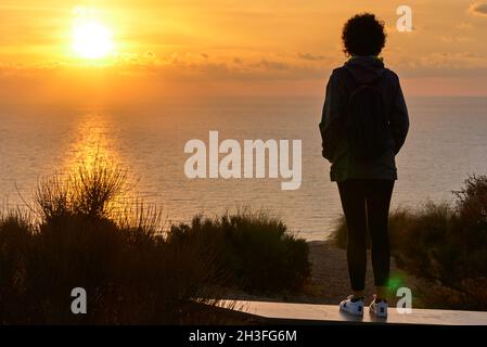 Une femme de randonnée de derrière regardant le lever du soleil sur la mer Banque D'Images