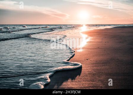 Magnifique coucher de soleil en Italie, Bibione, au bord de la mer avec une lumière et des vagues étonnantes à l'avant, se mélangeant dans un magnifique paysage romantique. Banque D'Images